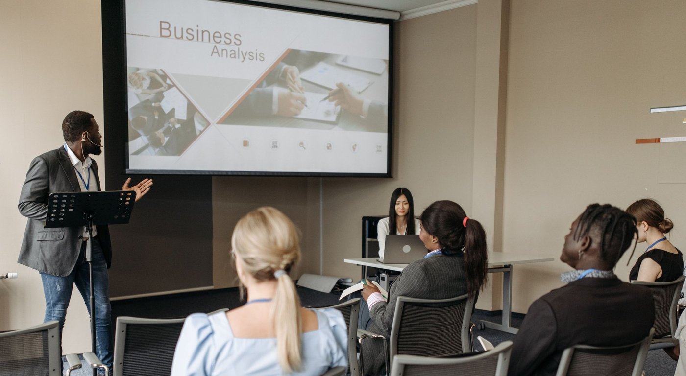 A facilitator presenting a business analysis slide to a seated group of training participants